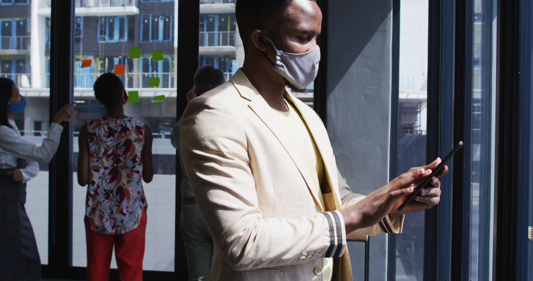 African American businessman using tablet while wearing face mask - Free Images, Stock Photos and Pictures on Pikwizard.com