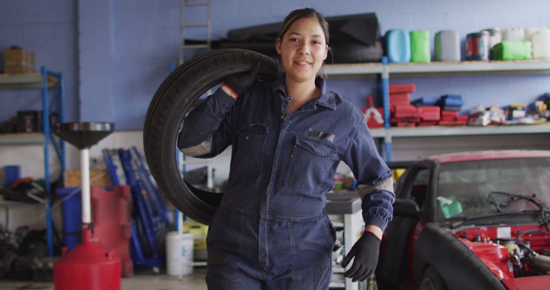 Female Auto Mechanic Carrying a Tire in a Garage - Free Images, Stock Photos and Pictures on Pikwizard.com