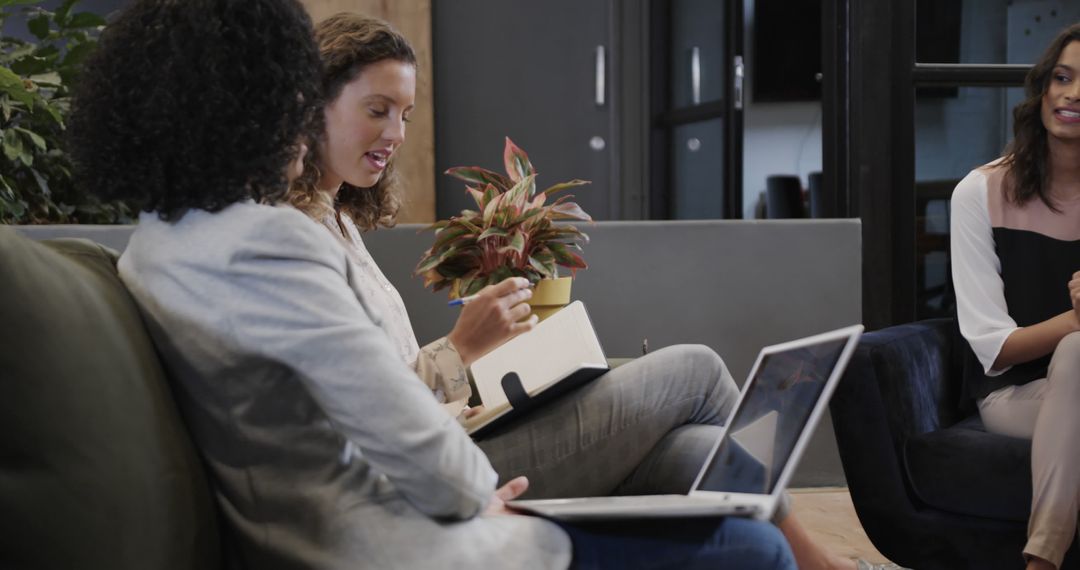 Diverse Female Colleagues Discussing Project in Modern Office Lounge