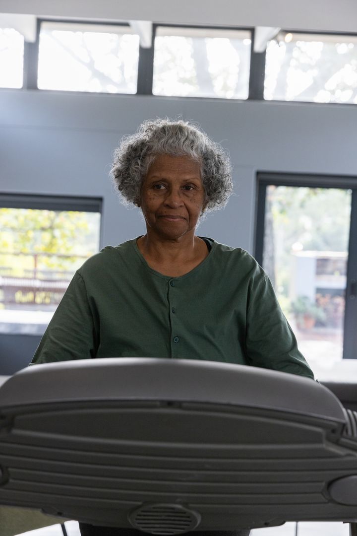 Senior Woman Exercising on Treadmill in Bright Gym