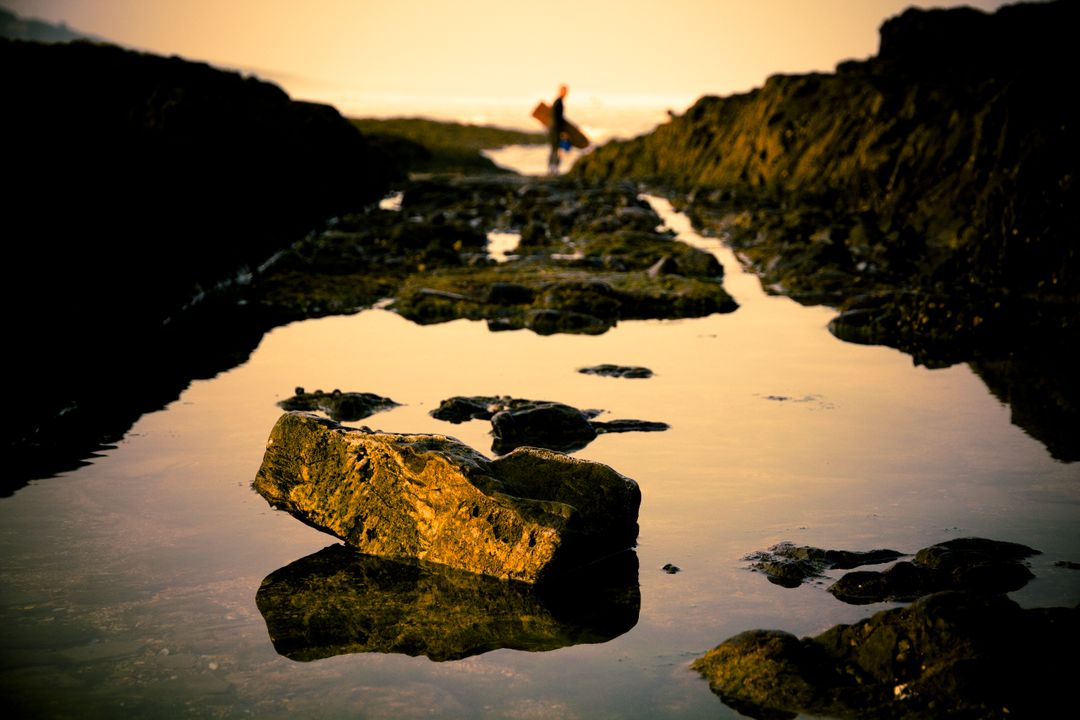 Solitary figure walking along rocky coastline at sunset - Free Images, Stock Photos and Pictures on Pikwizard.com