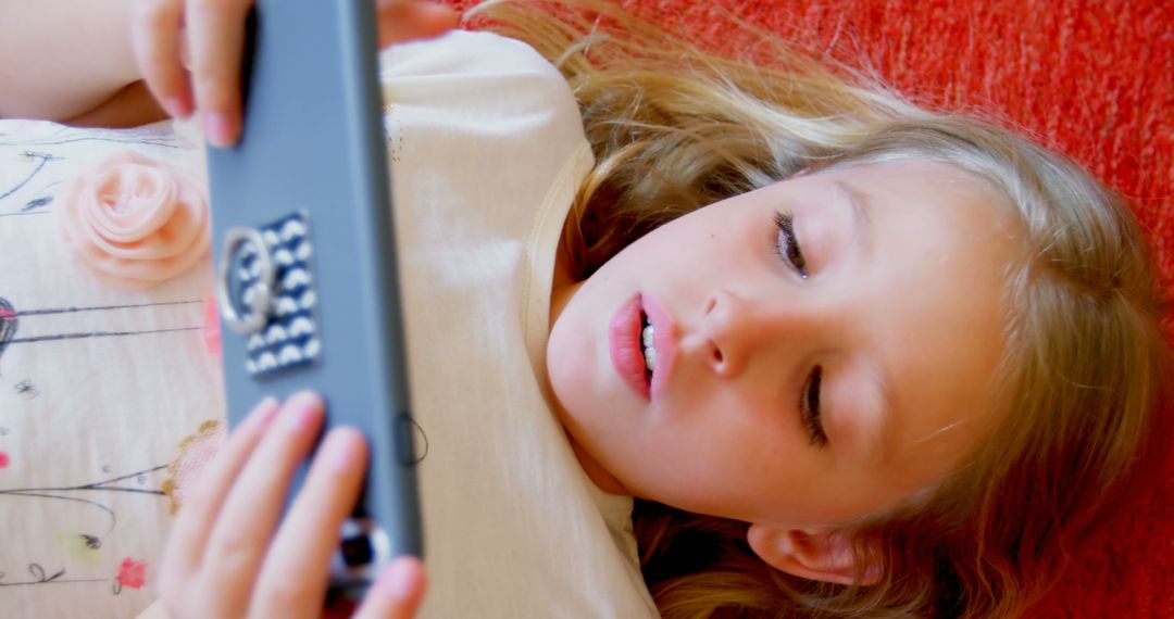 Girl Focused on Smartphone Lying on Red Couch