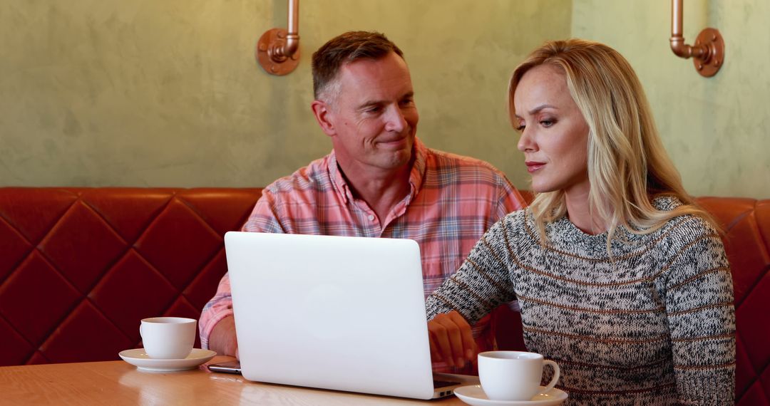 Middle-aged Couple Collaborating on Laptop in Cozy Cafe