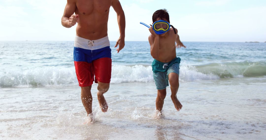 Father and son having fun with waves on the beach - Free Images, Stock Photos and Pictures on Pikwizard.com