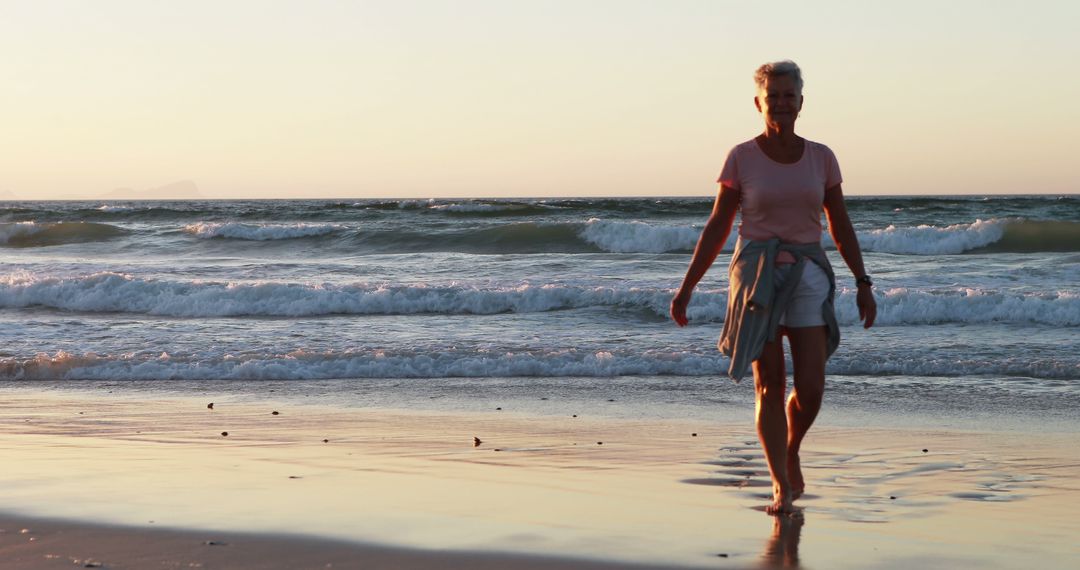 Older Woman Walking on Beach During Sunset - Free Images, Stock Photos and Pictures on Pikwizard.com