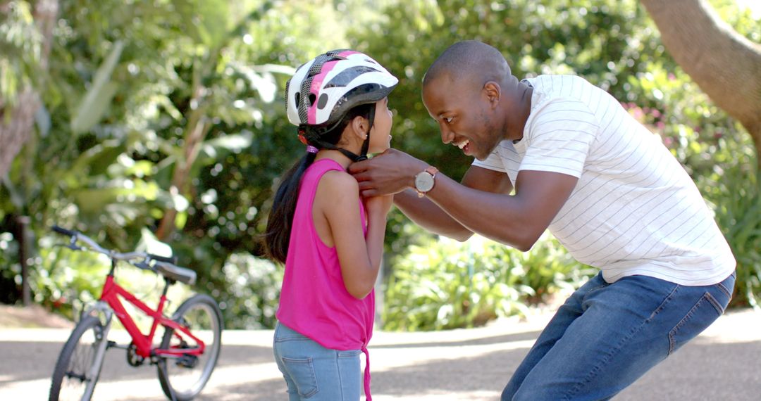 Father Adjusting Daughter's Helmet for Safe Cycling Adventure