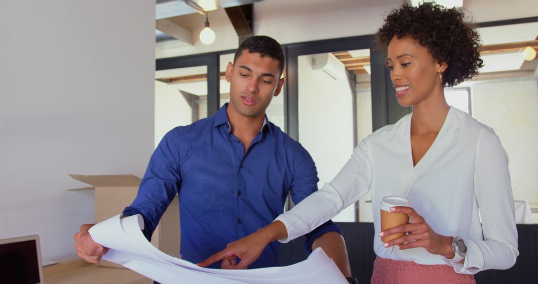 Professional Colleagues Analyzing Blueprints in Office Setting