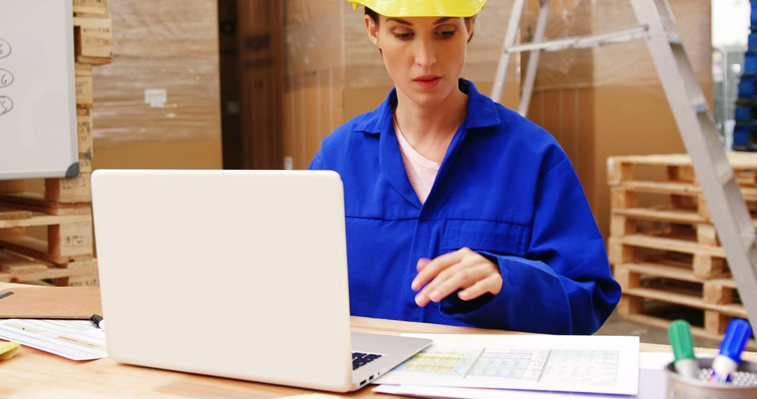 Warehouse Worker in Safety Gear Using Laptop for Inventory Management - Free Images, Stock Photos and Pictures on Pikwizard.com