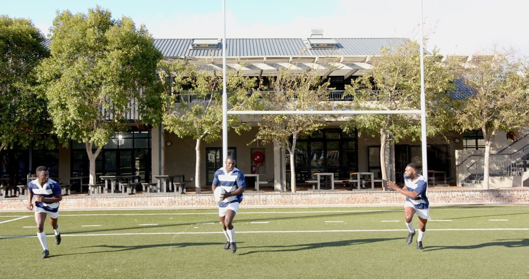 Rugby Players Passing Ball Underneath Goalpost in Action
