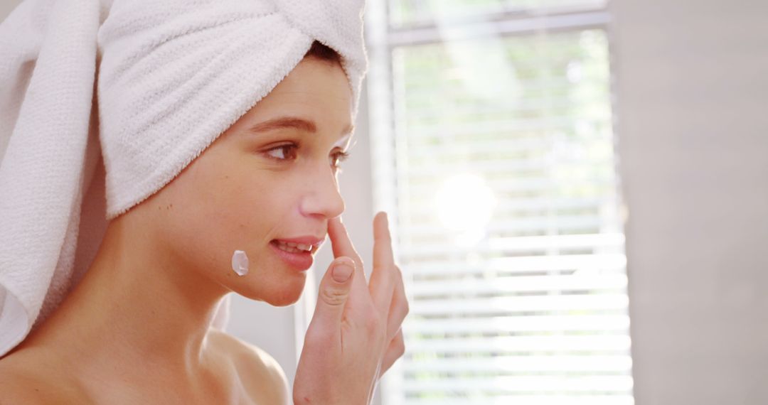 Woman Applying Skincare Cream After Shower in Bright Bathroom - Free Images, Stock Photos and Pictures on Pikwizard.com