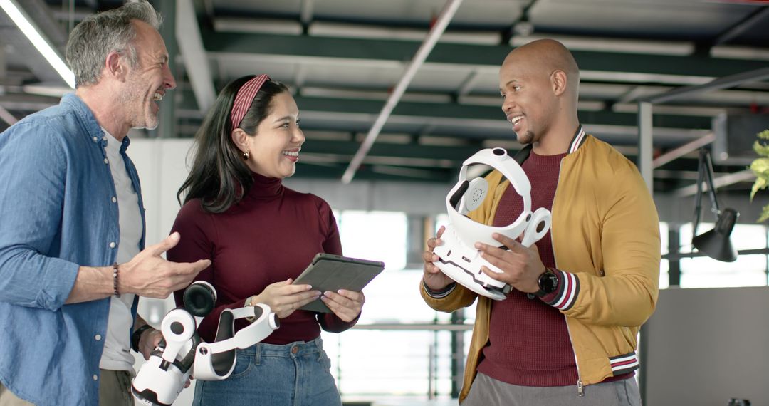 Diverse team testing VR headset prototype while collaborating with tablet in modern office