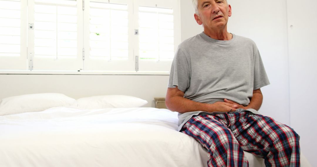 Mature man having stomach pain at home - Free Images, Stock Photos and Pictures on Pikwizard.com