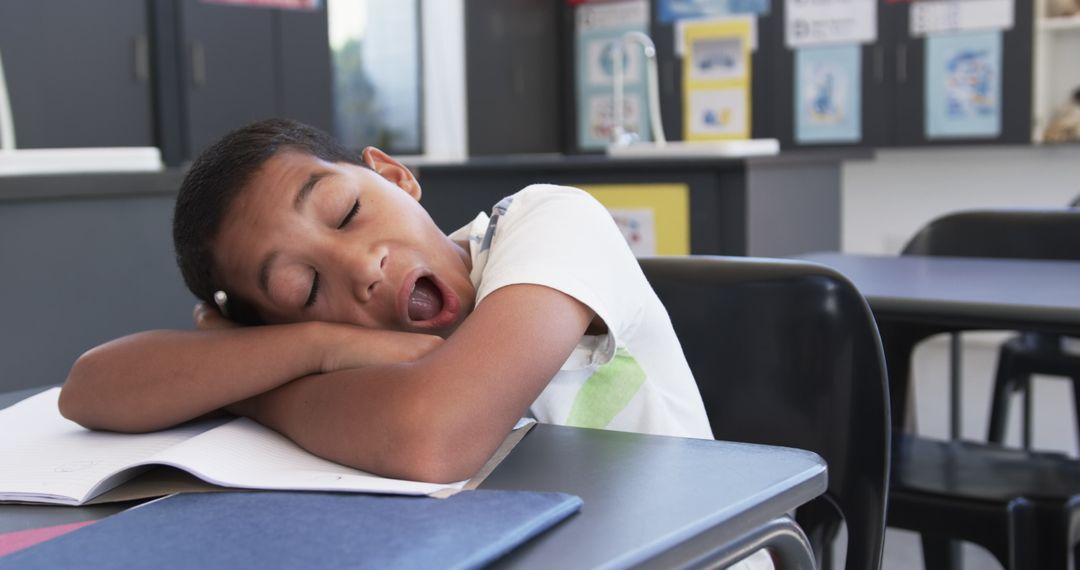Tired Young Student Yawning in Classroom During Lesson