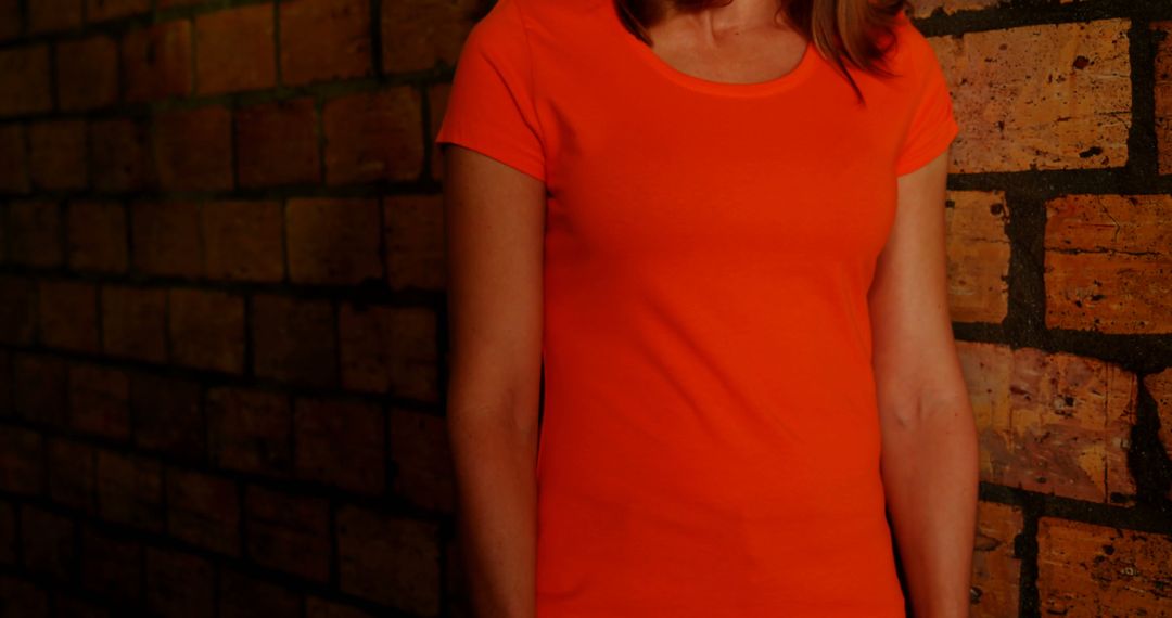 Woman in Orange T-shirt Against Brick Wall - Free Images, Stock Photos and Pictures on Pikwizard.com