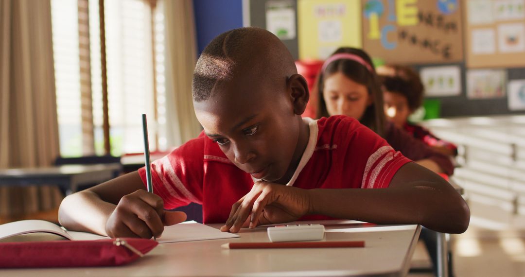 Portrait of african american schoolboy sitting in class, making notes, looking at camera - Free Images, Stock Photos and Pictures on Pikwizard.com