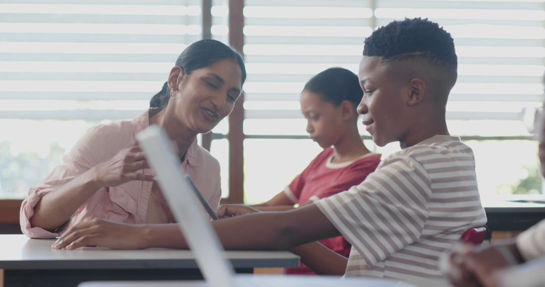 Teacher Assisting Students with Laptop During Classroom Lesson