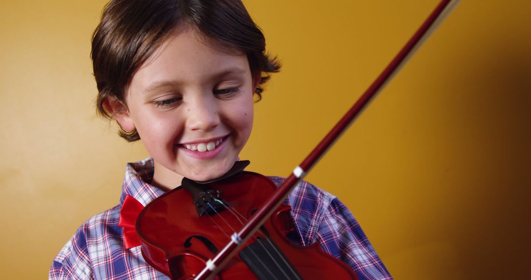 Boy Smiling While Playing Violin Against Yellow Background - Free Images, Stock Photos and Pictures on Pikwizard.com