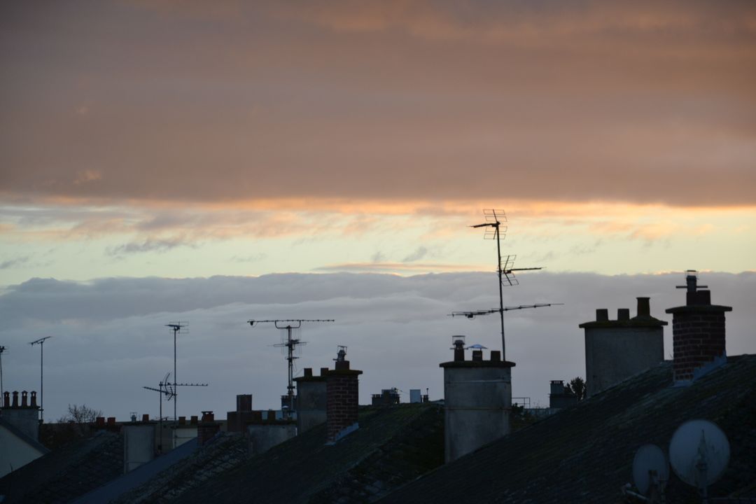 Sunset Over Rooftops with TV Antennas Silhouetted Against Sky - Free Images, Stock Photos and Pictures on Pikwizard.com