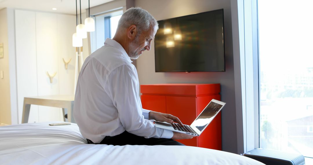 Senior Businessman Working on Laptop in Modern Hotel Room - Free Images, Stock Photos and Pictures on Pikwizard.com