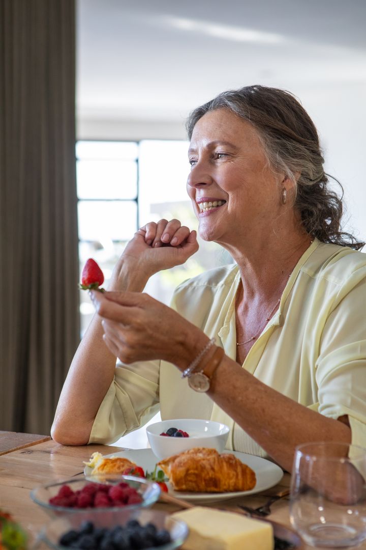 Senior Woman Enjoying Breakfast with Fresh Berries and Pastries