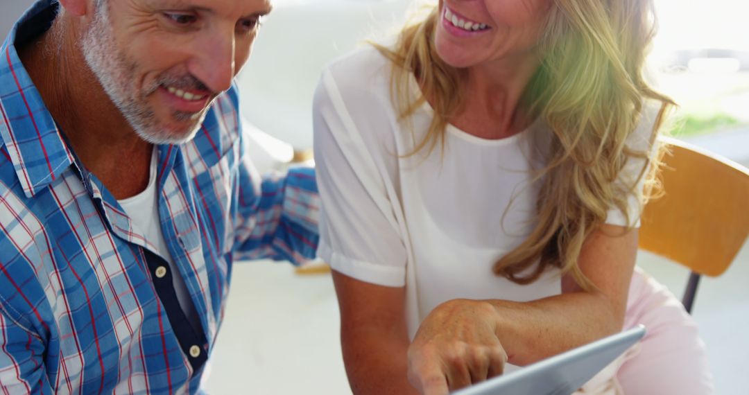 Mature Couple Using Tablet and Smiling at Home