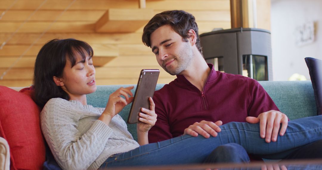 Image of back view of happy diverse couple sitting on sofa with smartphone - Free Images, Stock Photos and Pictures on Pikwizard.com