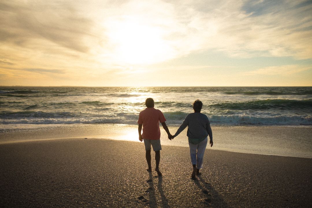 Senior Couple Holding Hands Walking on Beach at Sunset - Free Images, Stock Photos and Pictures on Pikwizard.com