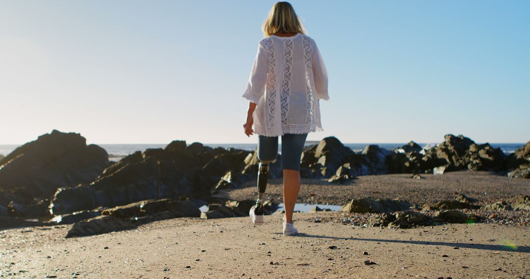 Woman with Prosthetic Leg Walking on Rocky Beach - Free Images, Stock Photos and Pictures on Pikwizard.com