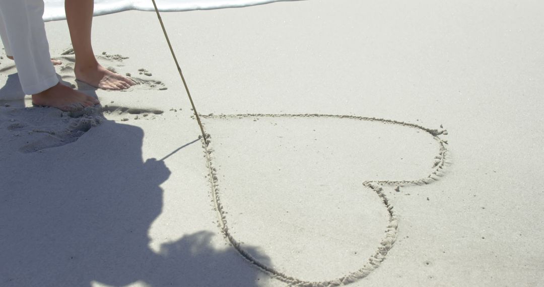 Couple Drawing Heart in Sand on Beach with Wooden Stick - Free Images, Stock Photos and Pictures on Pikwizard.com