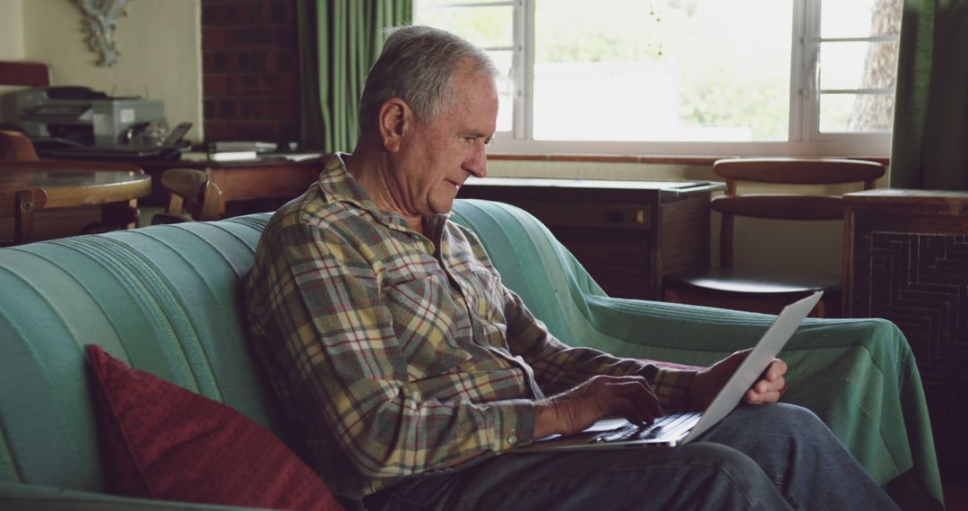 Elderly Man Using Laptop on Sofa in Cozy Living Room - Free Images, Stock Photos and Pictures on Pikwizard.com