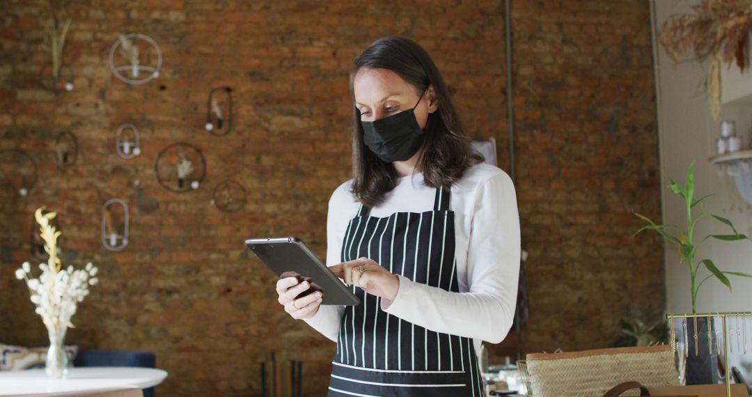 Female Masked Barista Using Digital Tablet in Coffee Shop - Free Images, Stock Photos and Pictures on Pikwizard.com