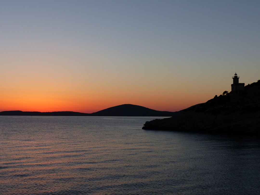 Beautiful Sunset Over Calm Sea With Silhouetted Lighthouse - Free Images, Stock Photos and Pictures on Pikwizard.com