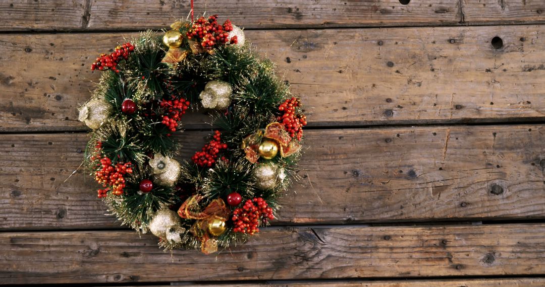 A Christmas wreath with gold and red accents brings festive warmth to a rustic setting. - Free Images, Stock Photos and Pictures on Pikwizard.com