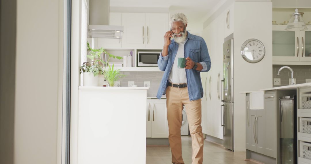 Senior Man Drinking Coffee While Talking on Phone in Modern Kitchen Interior - Free Images, Stock Photos and Pictures on Pikwizard.com