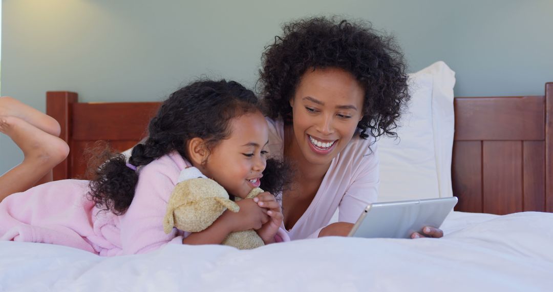 Mother and Daughter Reading from Digital Tablet While Relaxing on Bed - Free Images, Stock Photos and Pictures on Pikwizard.com