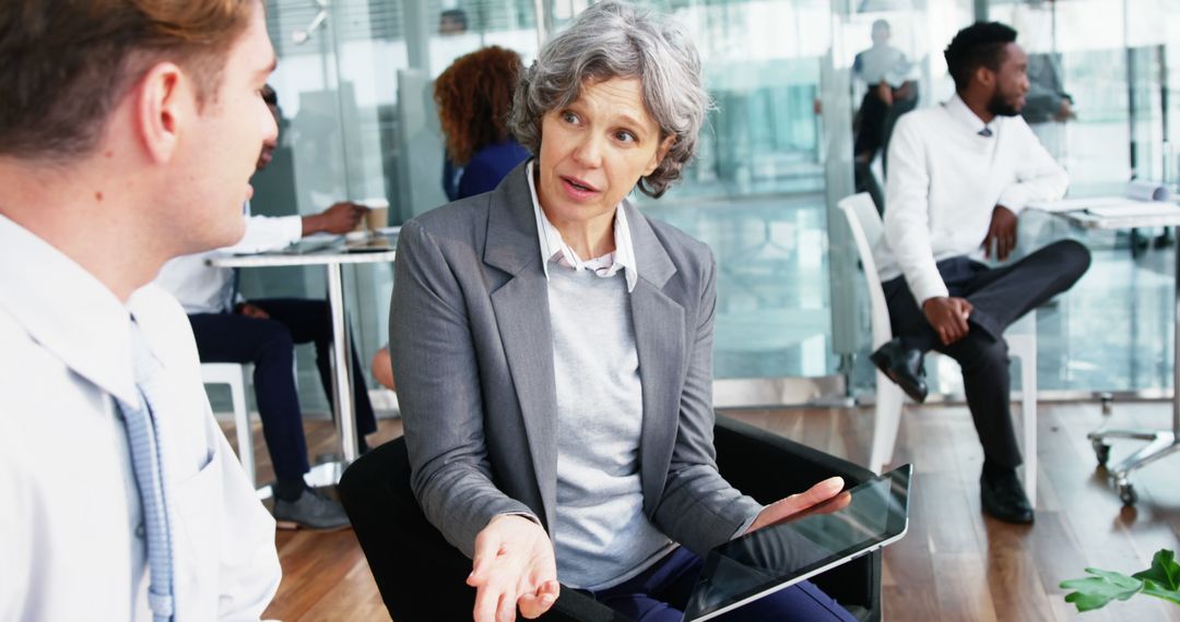 Senior Businesswoman Discussing Strategy with Colleagues in Modern Office - Free Images, Stock Photos and Pictures on Pikwizard.com