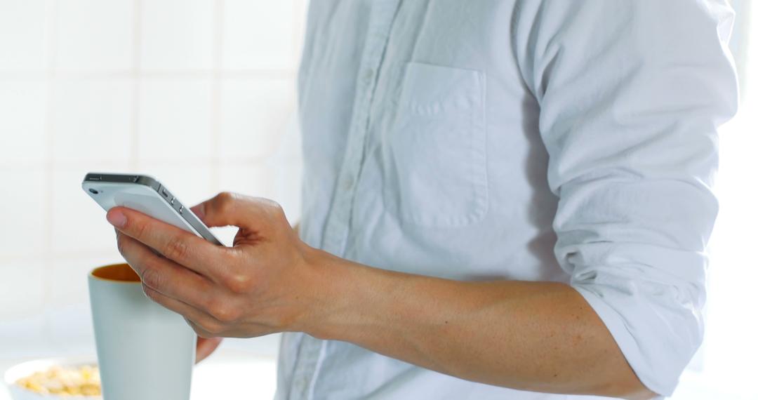 Person Holding Smartphone and White Mug in Casual Setting - Free Images, Stock Photos and Pictures on Pikwizard.com