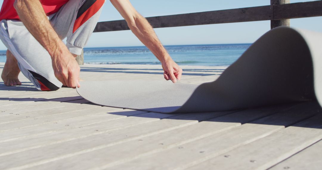 Preparing Yoga Mat on Beach Wooden Deck for Outdoor Exercise - Free Images, Stock Photos and Pictures on Pikwizard.com