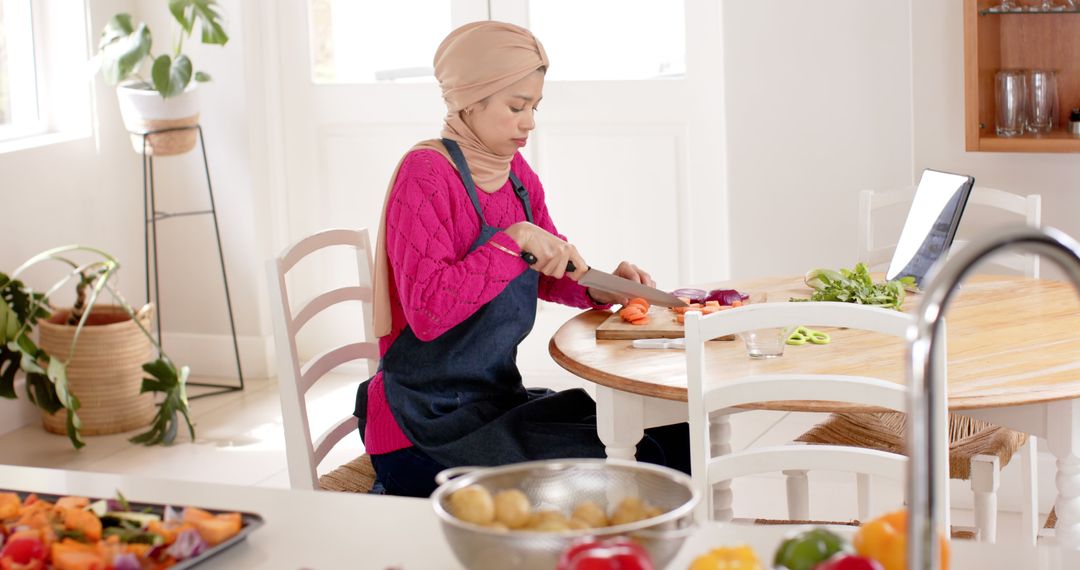 Woman in Hijab Preparing Vegetables in Sunlit Kitchen - Free Images, Stock Photos and Pictures on Pikwizard.com