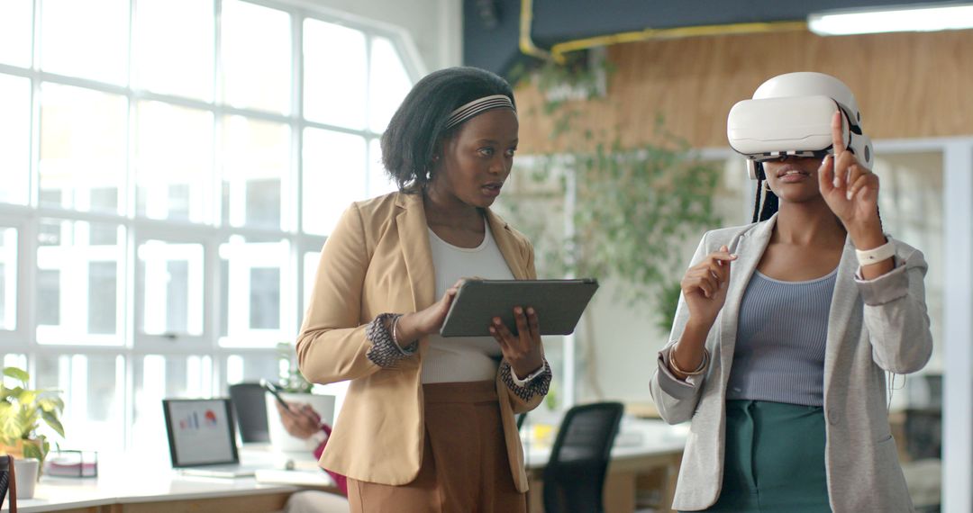 Businesswomen Testing Virtual Reality Headset in Modern Office Collaborating with Tablet