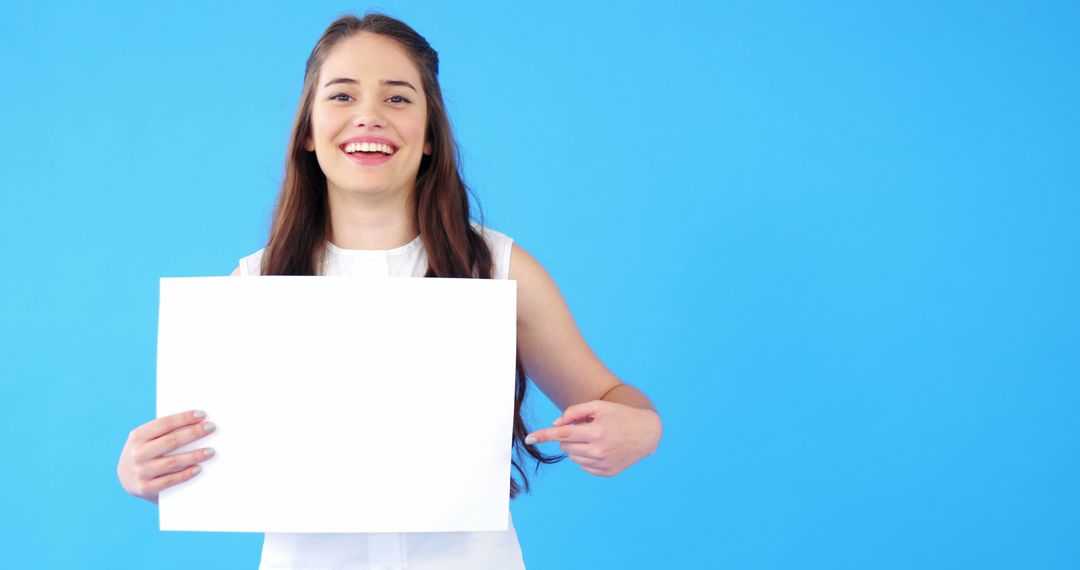 Smiling Woman Holding Blank Sign on Blue Background - Free Images, Stock Photos and Pictures on Pikwizard.com