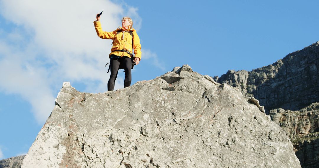 Woman on Rocky Peak Taking Selfie with Bright Blue Sky - Free Images, Stock Photos and Pictures on Pikwizard.com