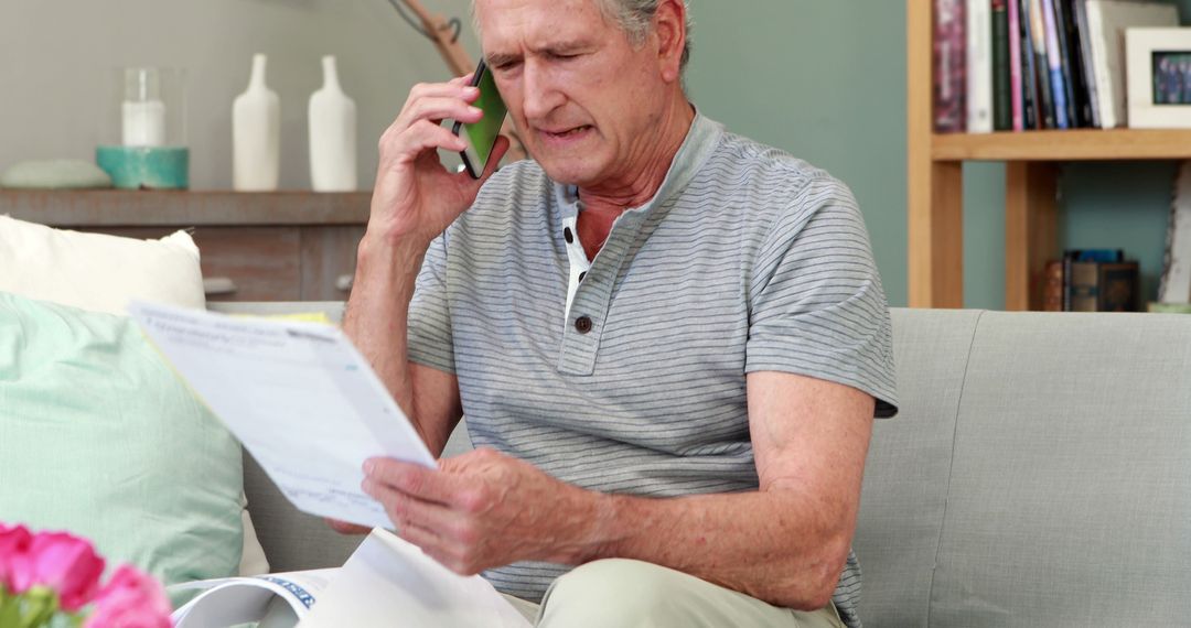 Senior man talking on phone and holding financial documents at home - Free Images, Stock Photos and Pictures on Pikwizard.com