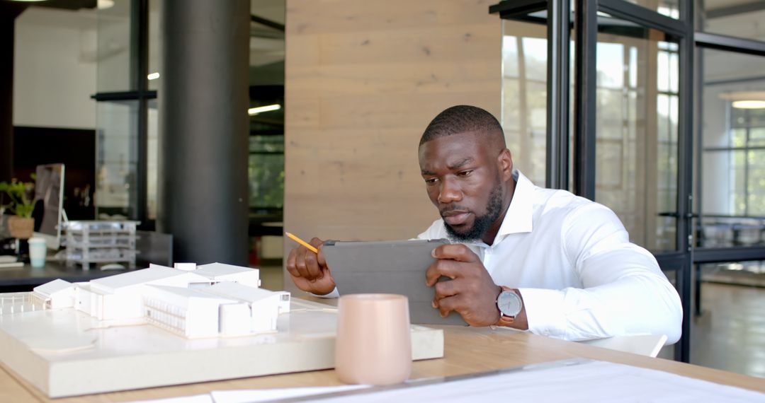 Architect Using Tablet for Building Model Review in Modern Office