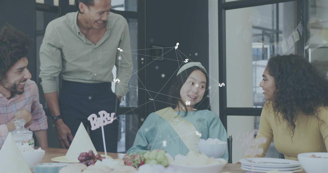 Office team celebrating baby shower for colleague wearing sash and party hat