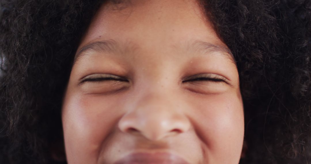 Close-Up of Smiling Child with Curly Hair and Eyes Closed - Free Images, Stock Photos and Pictures on Pikwizard.com