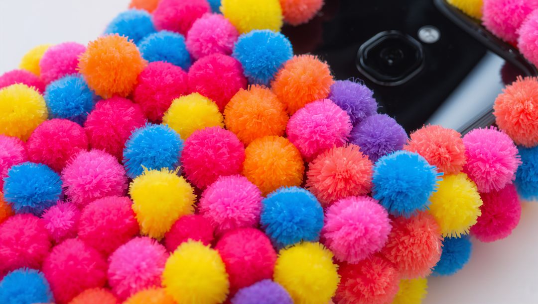 Decorating Smartphone with Neon Pom-Pom Case Closeup Colorful Fuzzy Texture Glossy Camera Macro