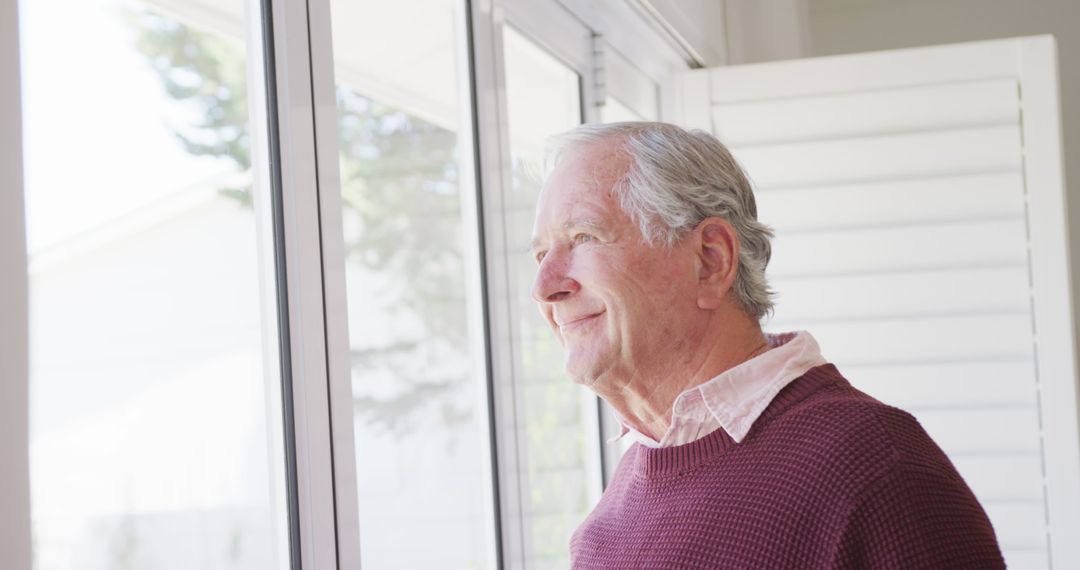 Smiling Elderly Man Looking Out Window, Wearing Sweater Indoors - Free Images, Stock Photos and Pictures on Pikwizard.com