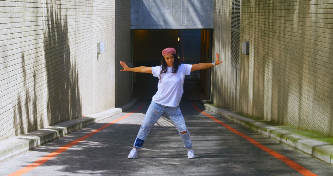 Confident Young Woman Dancing in Sunlit Alley - Free Images, Stock Photos and Pictures on Pikwizard.com