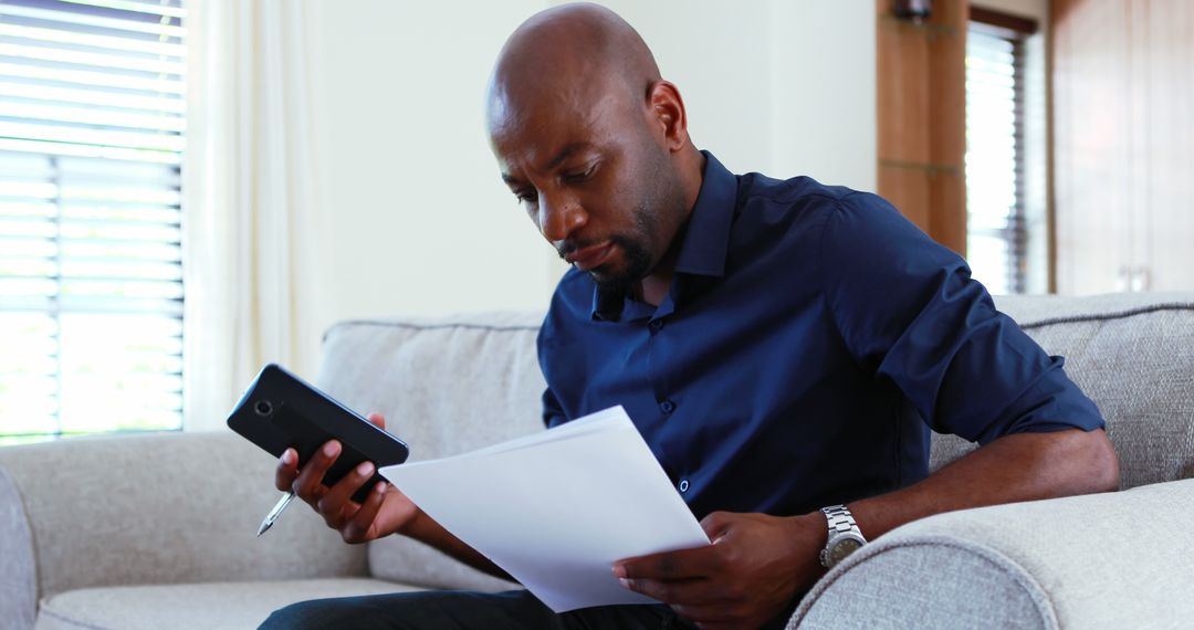 Man Reviewing Documents on Couch in Modern Living Room - Free Images, Stock Photos and Pictures on Pikwizard.com